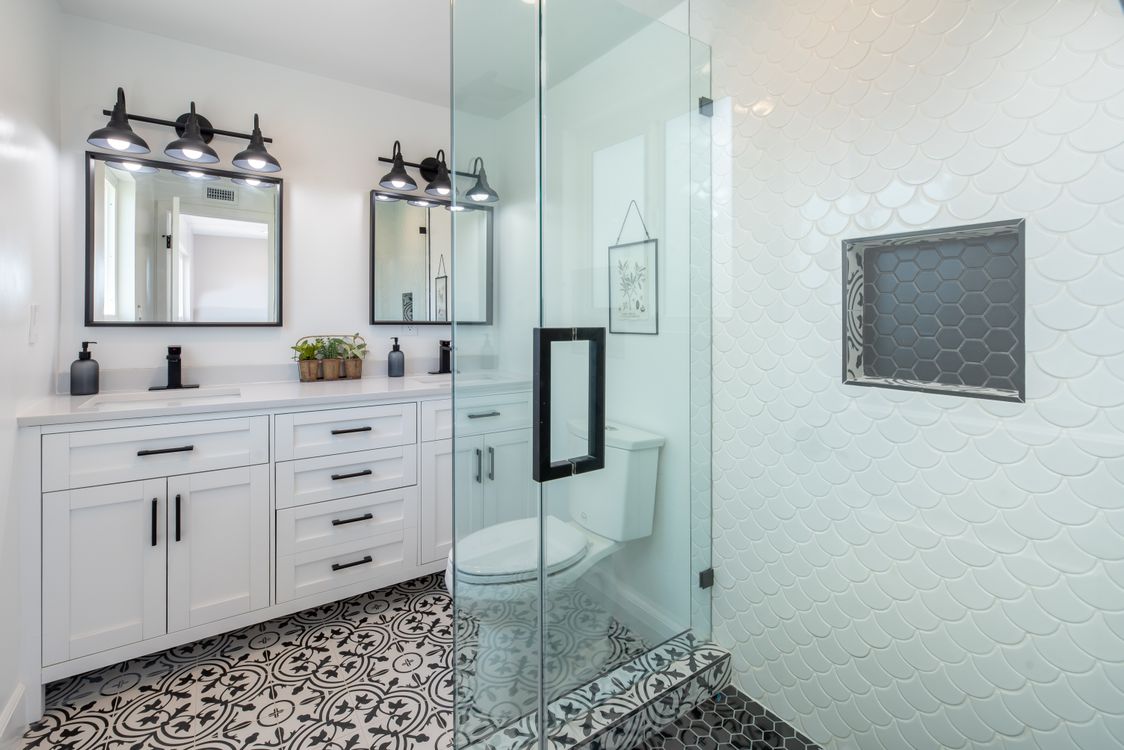 Nette witte badkamer met glazen douche en patroonvloer