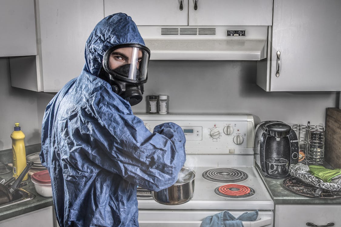 Man in beschermend pak bij het inspecteren van een gaskeuken
