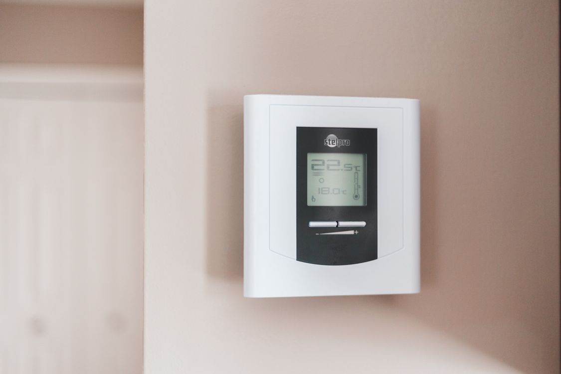 Moderne digitale thermostaat aan de muur die de temperatuur weergeeft