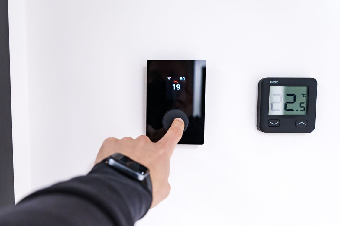 Hand stelt een digitale thermostaat in een moderne woning in