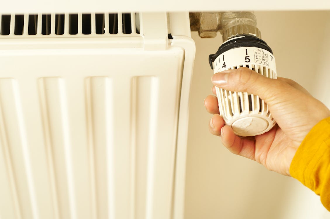 Hand die de thermostaat van een radiator instelt om de waterdruk te controleren