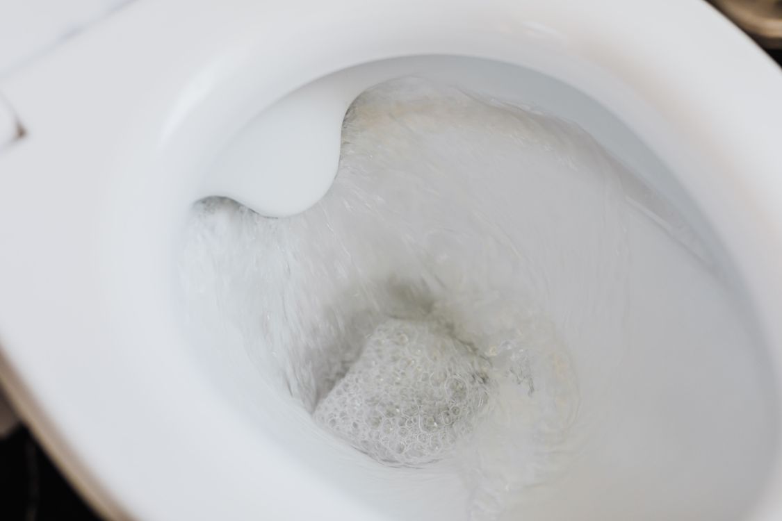 Wit wc-pot met schuimend water bij doorspoelen