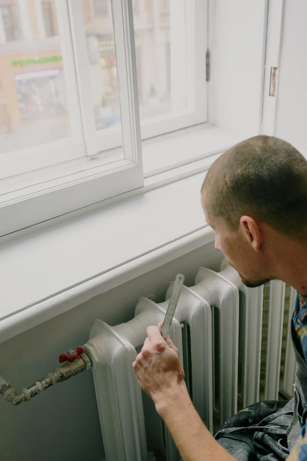 Loodgieter met gereedschapsgordel bezig aan leidingwerk in een woning