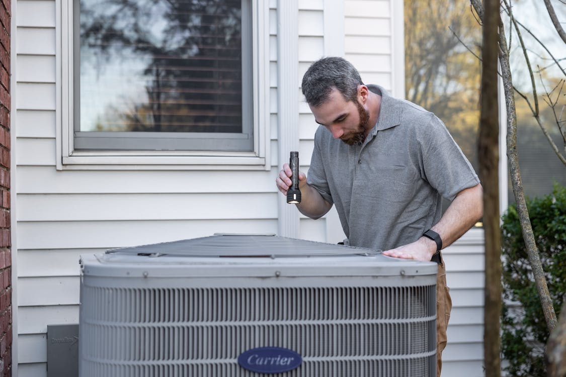 Technicus inspecteert de buitenunit van een warmtepomp