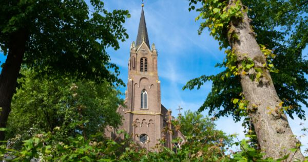 Neogotische kerk van Dongen omgeven door groene bomen in de zomer